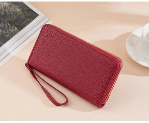 Red litchi grain long leather wallet with gold zipper and wristlet on professional background