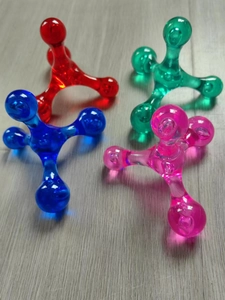 Detail view of four transparent handheld roller massagers in red, green, blue, and pink