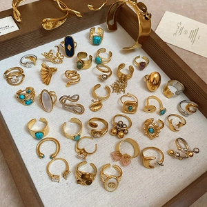 Flat lay of 18k gold-plated cuff bracelets and rings with turquoise and pearls in a tray