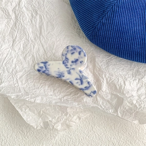 Close-up of blue and white marble pattern hair claw clip with a glossy acetate finish