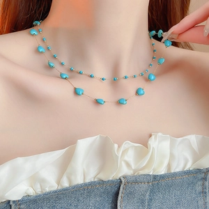 Close-up of double-layered gold necklace with blue stone beads on model's neck