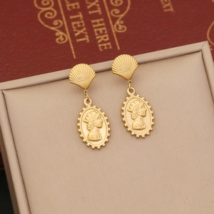 Golden vintage cameo earrings with shell studs on display over a classic book