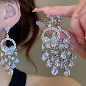 Détail de boucles d'oreilles argentées avec papillons en zircon et pampilles en cristal