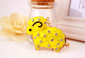 Macro detail of cute yellow enamel sheep keychain with sparkling rhinestones and gold hook