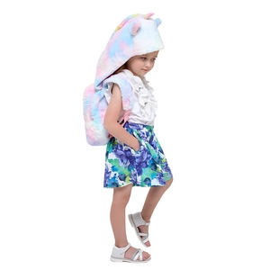 Seitenansicht eines Mädchens mit Einhorn-Plüschrucksack und passender Batik-Kapuzenmütze