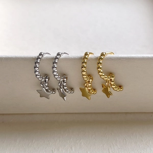 Detail of S925 sterling silver hoop earrings with bead texture and star charms in gold and silver