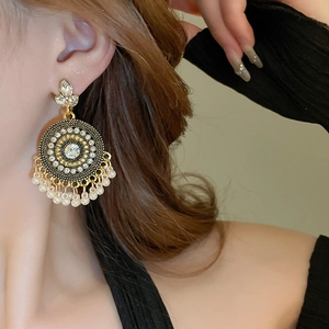 Detail of bohemian drop earrings with gold filigree, white rhinestones and pearls