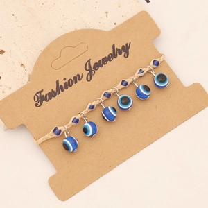 Macro detail of Bohemian evil eye woven bracelet with seven blue beads on card