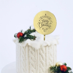 Close-up of golden Merry Christmas acrylic cake topper on a festive white cake