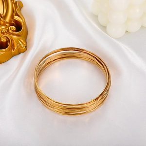 Detailed close-up of multi-layer gold alloy bangles set on white silk background