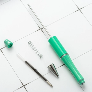 Disassembled DIY creative plastic beaded ballpoint pen with green barrel and components