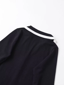 Detailed view of the black knit dress featuring a white contrast trim on the collar