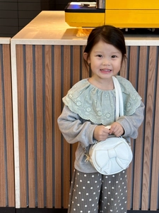 Mini round white kids bag with bow detail held by child in Korean style outfit