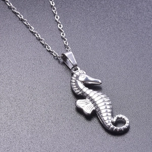 Detailed macro shot of a silver seahorse pendant on a chain over a black background