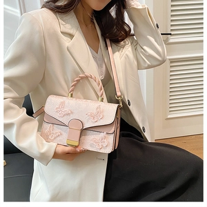 Detail of pink shoulder bag with 3D butterfly appliqués worn by a model in a suit