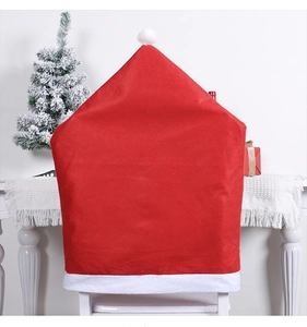 Detail of red Santa hat chair cover in festive setting with snowy Christmas tree background