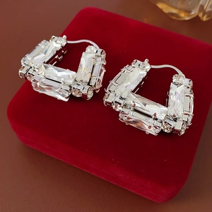 Gros plan de boucles d'oreilles argentées en U avec cristaux sur boîte en velours rouge