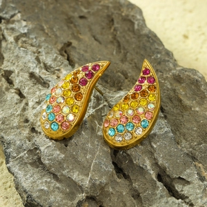 Luxury gold teardrop earrings with colorful crystals on grey natural rock surface