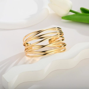 Detail of multi-layered 18K gold-plated coil open bracelet with aesthetic tulip background