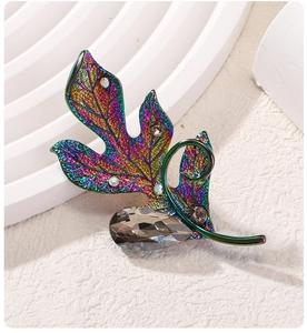 Macro detail of iridescent leaf brooch featuring colorful gradients and grey crystal droplet