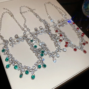 Detail of necklace set with bow-knot chains and teardrop gemstones in emerald and red