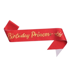 Close-up of red satin sash with golden Birthday Princess text and crown detail