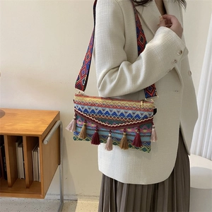 Close-up of bohemian woven crossbody bag with colorful tassels and jacquard wide strap