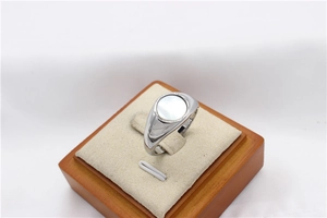 Close-up of minimalist signet ring with round white shell inlay on a beige display stand