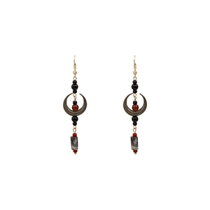 Macro shot of ethnic moon earrings with red beads and long pendants on white background