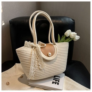 Detail of beige straw handbag with leather flap pearl clasp and decorative lace ribbon