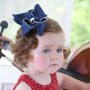 Detail of a navy blue bow hair clip with white scalloped edges on a young girl