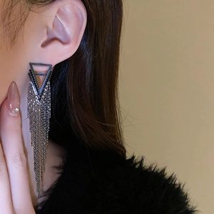 Close-up of elegant silver triangle tassel earrings with delicate hanging metal chains