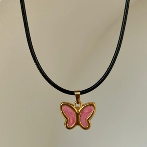 Detailed close-up of a vintage pink enamel butterfly pendant with 18k gold plating