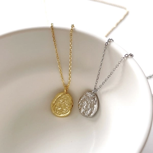 Detail of gold and silver hammered oval coin pendants on delicate silver necklaces