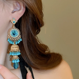 Close-up of vintage tassel earrings with gold finish and blue beads on a model