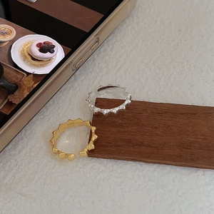 Detailed view of S925 sterling silver thorn rings in gold and silver on wood surface