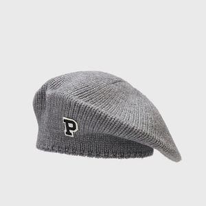 Detail of grey knitted beret featuring soft wool texture and embroidered P letter patch