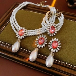 Détail de parure bijoux perles multicouches avec pierres roses sur plateau velours