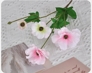 Detail of white and pink artificial butterfly ranunculus flowers on a white lace background