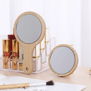 Detail view of round wooden hand mirrors on a minimalist desk with cosmetic props