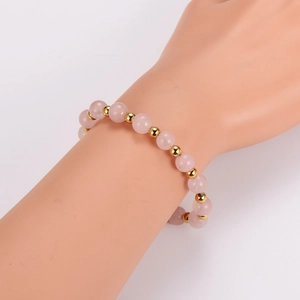 Pink crystal energy stone bracelet with gold spacer beads on female model wrist