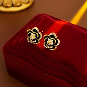 Close-up of vintage flower earrings with black enamel petals and pearl center on velvet