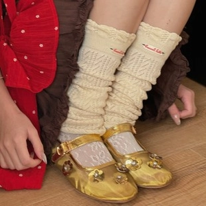 Close-up of cream knit socks with ruffle edges and hollow texture worn with Mary Jane shoes