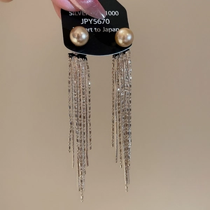 Close-up of champagne pearl drop earrings with elegant silver chain tassels on display