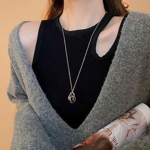 Detail of silver interlocking ring pendant necklace worn by model on black knit sweater