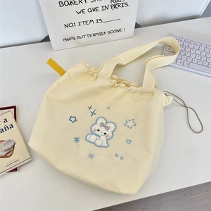 Detail of yellow canvas tote bag featuring cute bunny embroidery and drawstring closure