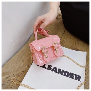 Detail of pink jelly mini handbag featuring gold buckles and fine metal chain strap