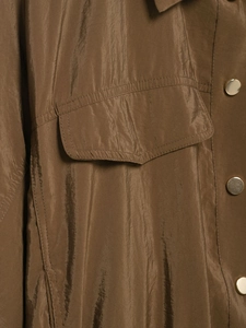 Détail de la chemise safari marron avec poche poitrine et boutons-pression dorés mats