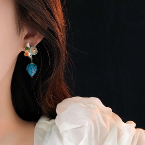 Close-up of blue strawberry pendant earring with colorful beads on model's ear