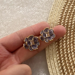 Vintage floral stud earrings with purple enamel and zircon stone in hand-held display